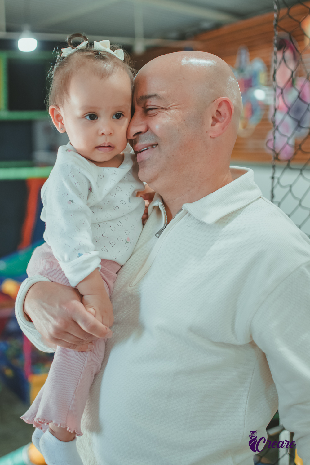 Uma bebê com seu padrinho, durante sua festa de aniversário de 1 ano.