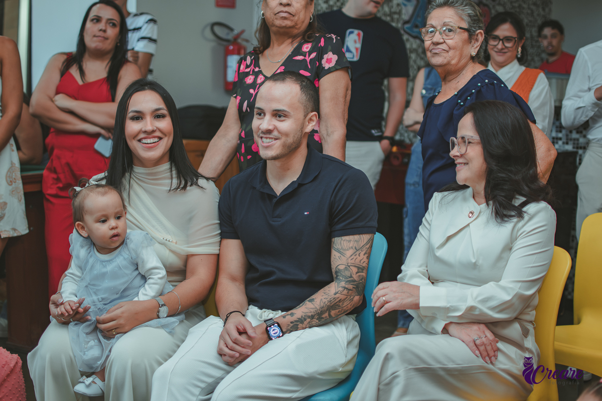 Uma familia sentando e assistindo a retrospectiva durante a festa de aniversário de 1 ano da bebê