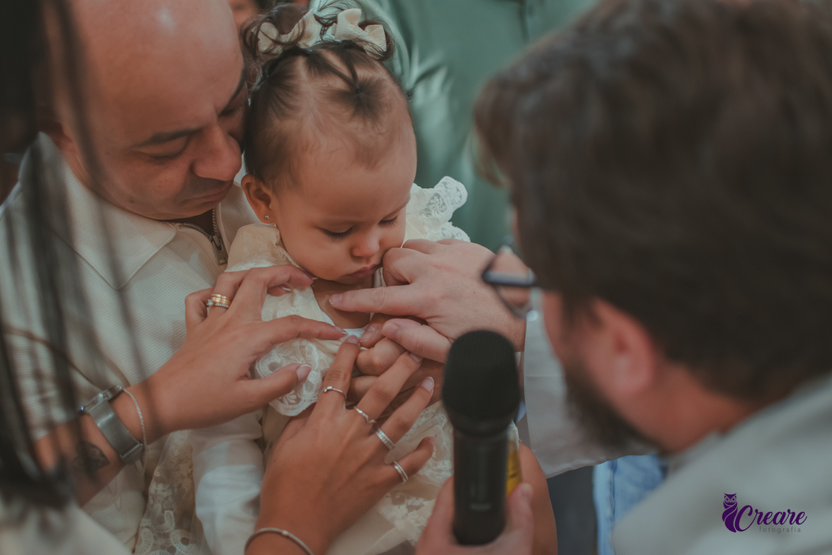 O padre ungindo o peito d euma bebê com oleo santo, durante o batizado na igreja católica.