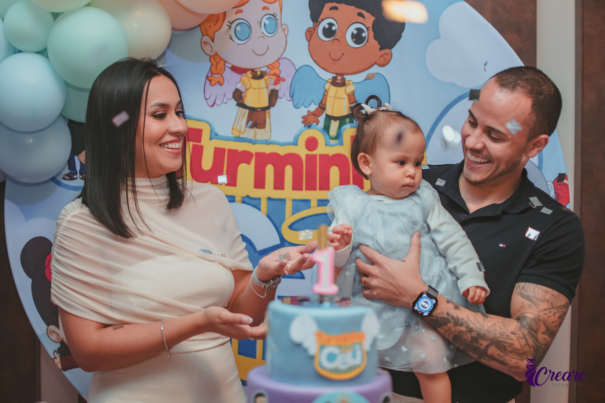 Uma família cantando parabéns enquanto papeis brilhantes caem, durante festa de aniversário de 1 ano.