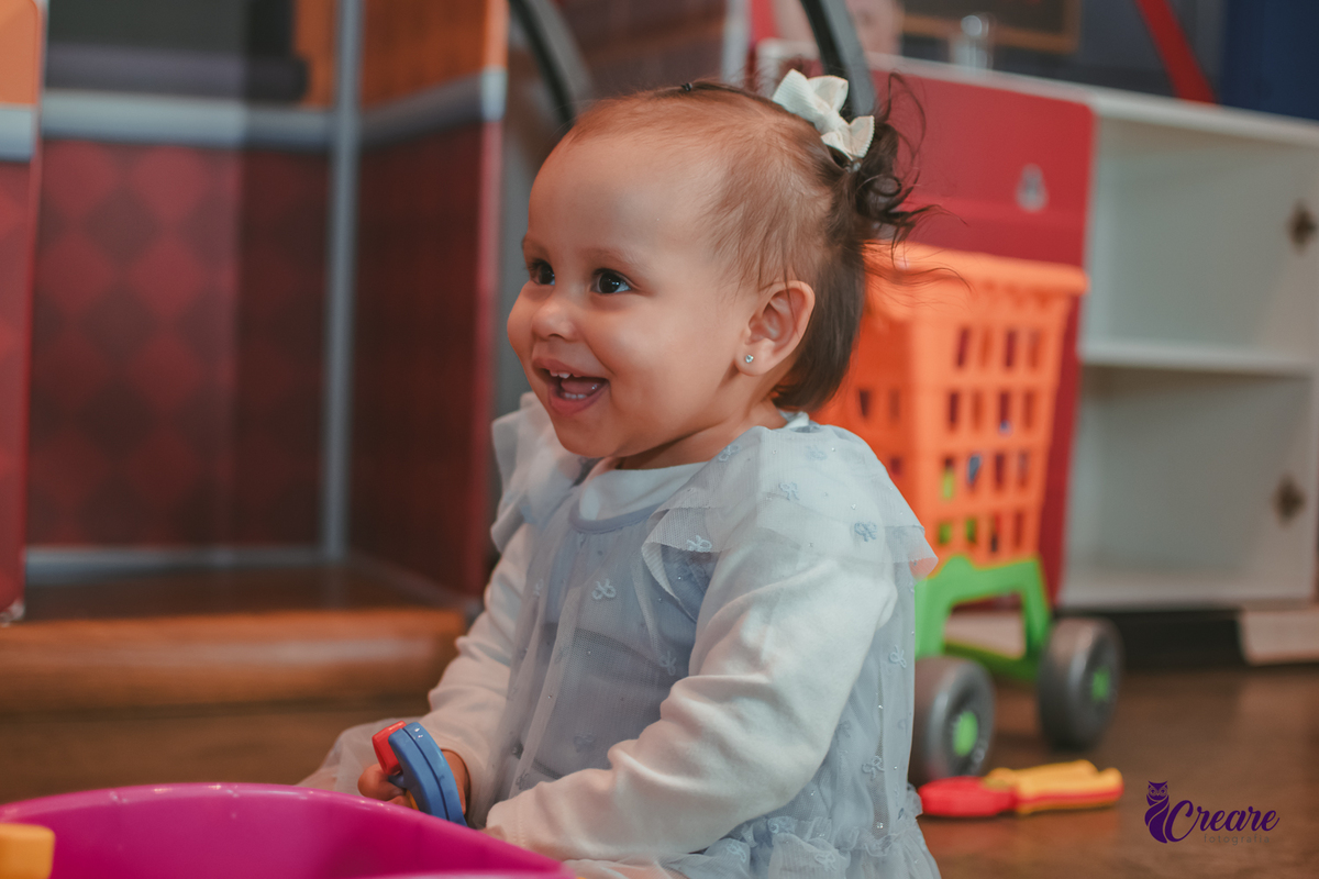 Uma bebê brincando com carrinho rosa em sua festa de aniversário de 1 ano.