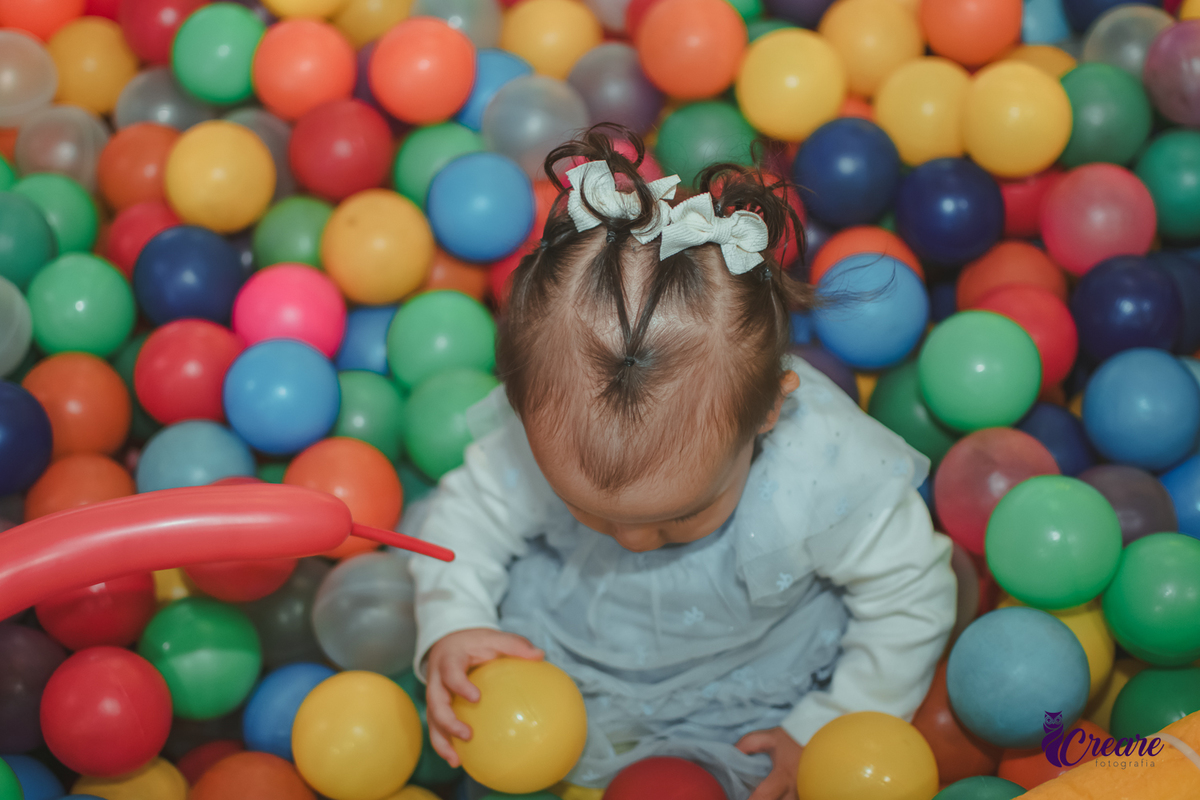 Uma bebê brincando nas piscina de bolinhas durante sua festa de aniversário de 1 ano.