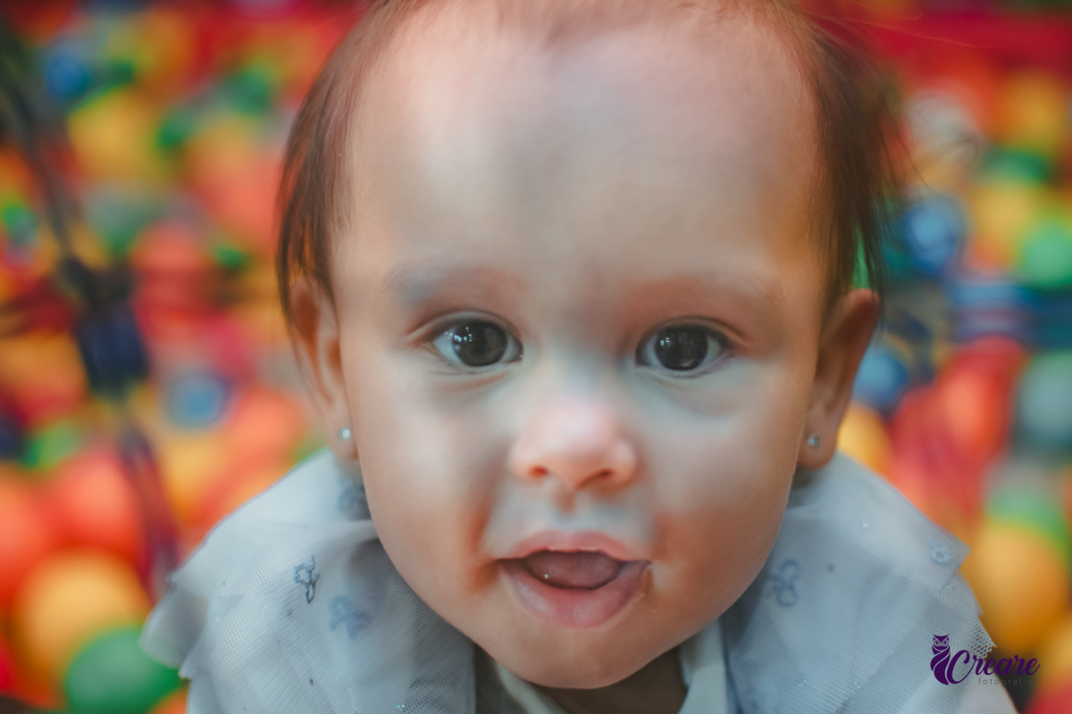 Uma bebê brincando nas piscina de bolinhas durante sua festa de aniversário de 1 ano.