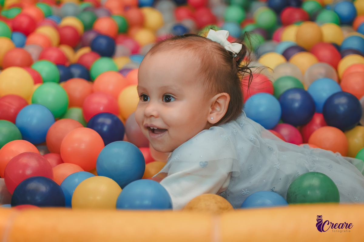 Uma bebê brincando nas piscina de bolinhas durante sua festa de aniversário de 1 ano.