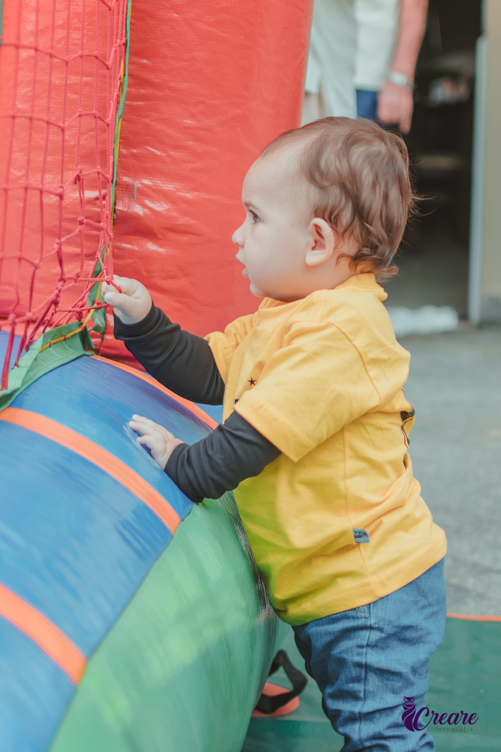 Bebê brincando em frente um pula pula durante seu aniversário de 1 ano.