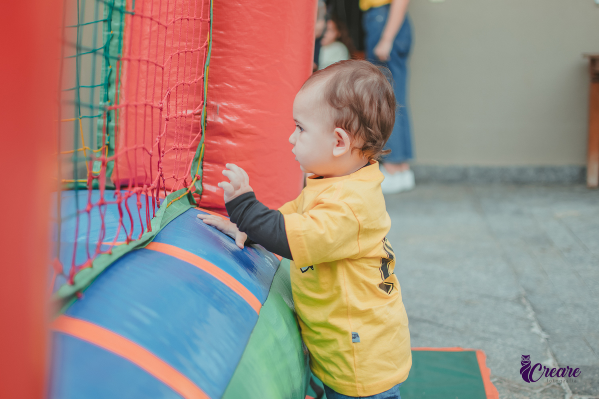 Bebê brincando em frente um pula pula durante seu aniversário de 1 ano.