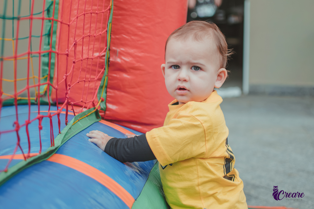 Bebê brincando em frente um pula pula durante seu aniversário de 1 ano.