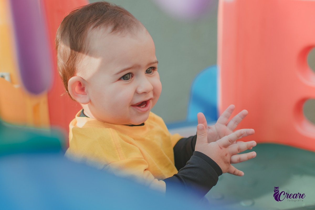 Um bebê sorrindo e batendo palmas durante seu aniversário de 1 ano.
