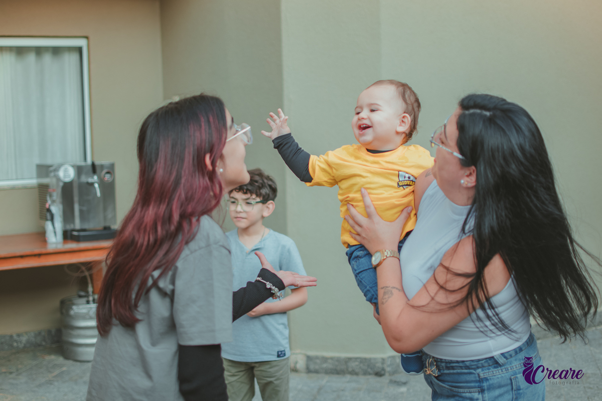 Uma mulher e uma menina brincam com um bebê durante uma festa de aniversário de 1 ano em casa.