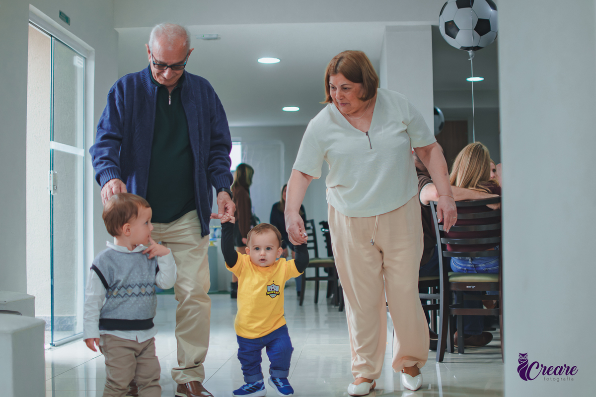 Um casal idoso andando de mãos dadas com um bebê, durante aniversário de 1 ano em Santo André.