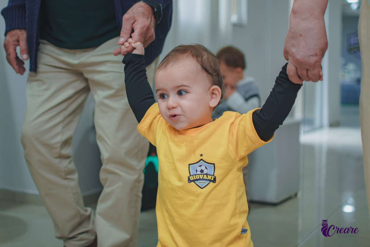 Um casal idoso andando de mãos dadas com um bebê, durante aniversário de 1 ano em Santo André.