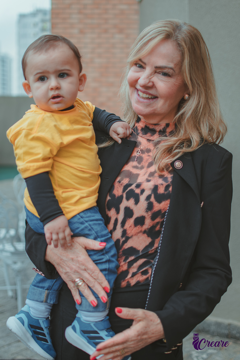 Um bebê brincando com sua avó, durante sua festa de aniversário em casa.