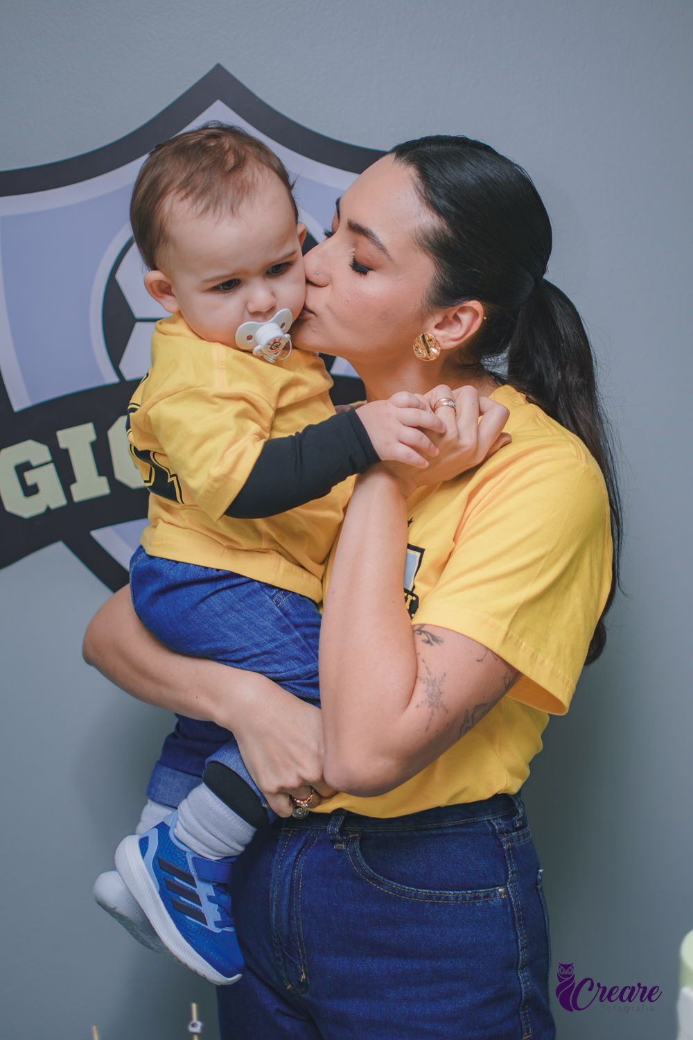 mulherbeijando seu bebê na buchecha durante festa de aniversário de 1 ano.