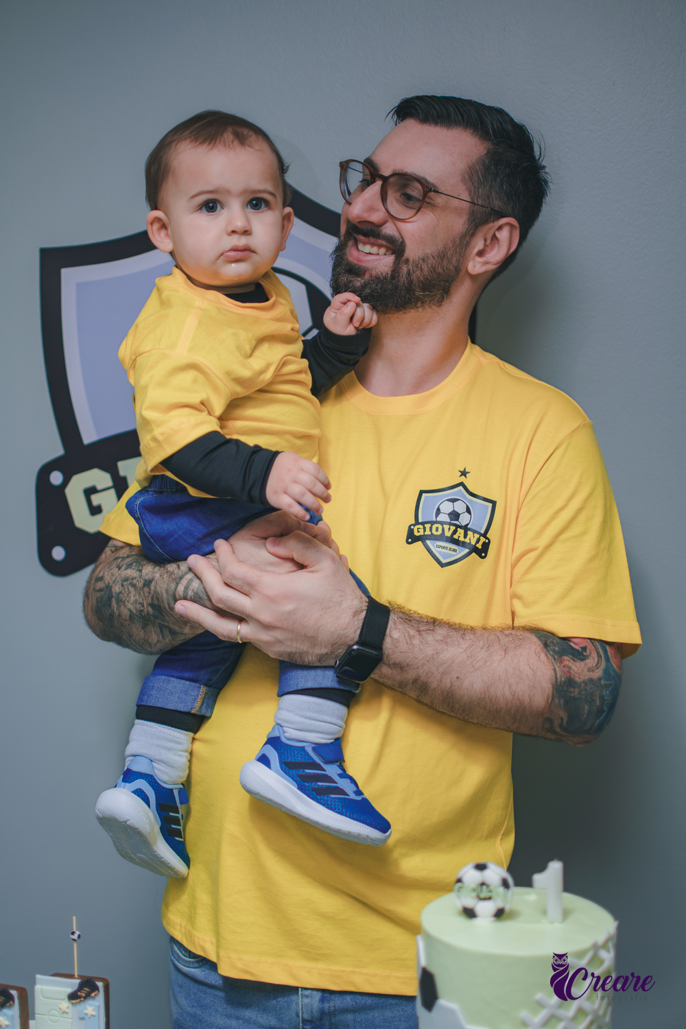 homemolhando para seu bebê de 1 ano e sorrindo, durante festa de aniversário de 1 ano.