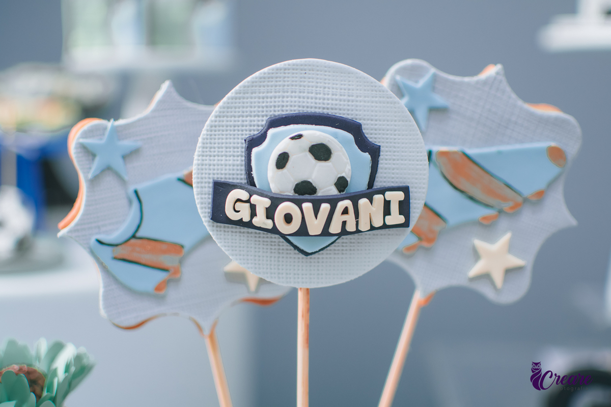 Pirulitos de chocolate decorados com uma chiteira e o nome Giovani, parte da decoração de festa de aniversário de 1 ano.