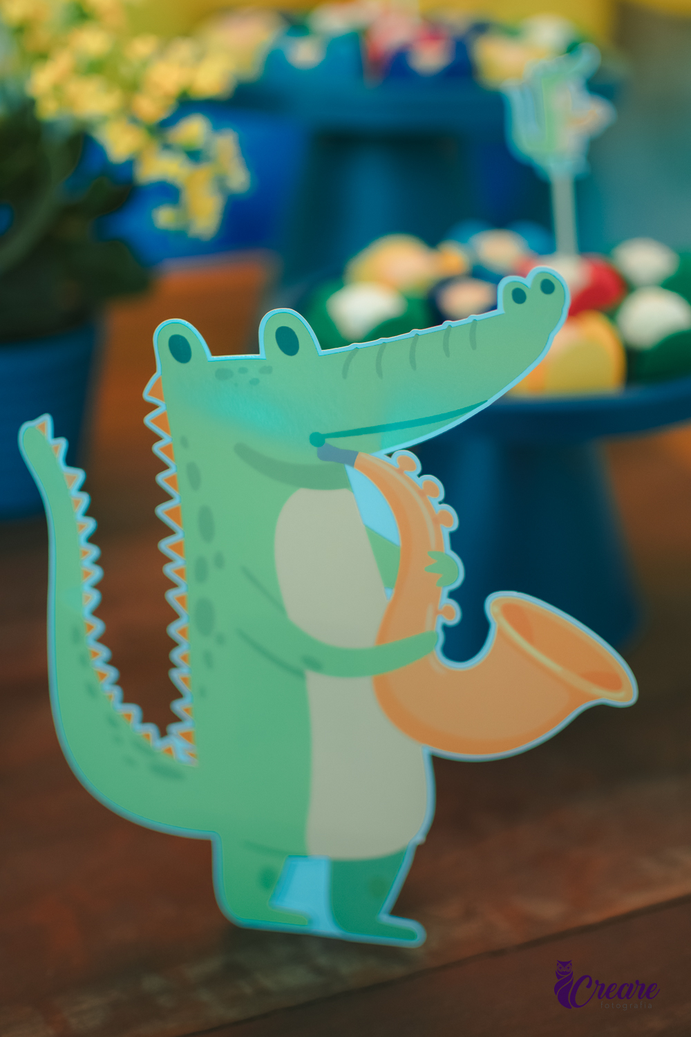Decoraçao de festa infantil com o tema banda dos animais, desenho de uma jacaré tocando saxofone. 