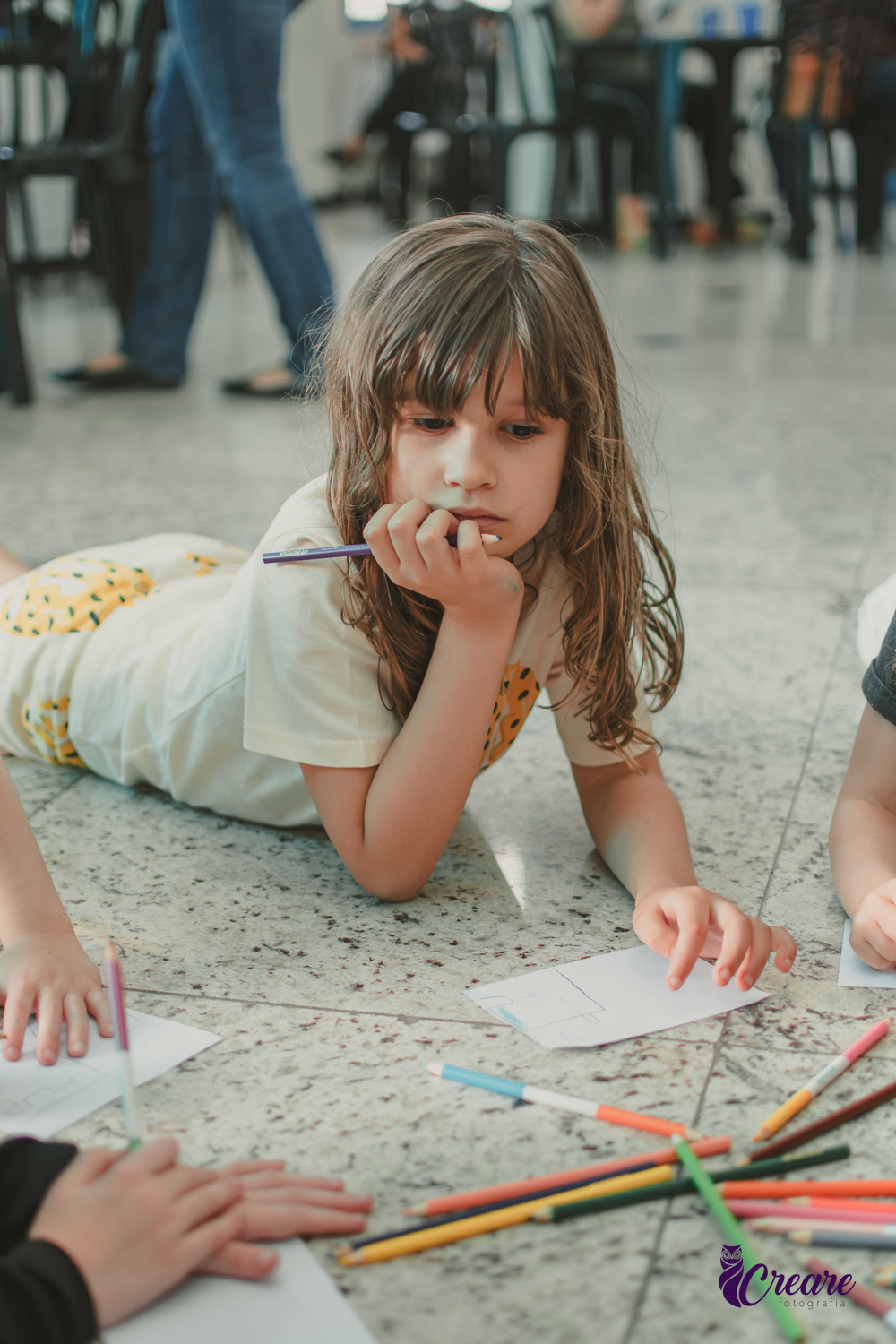 Uma criança desenhando no chão, durante festa de aniversário infantil em casa.