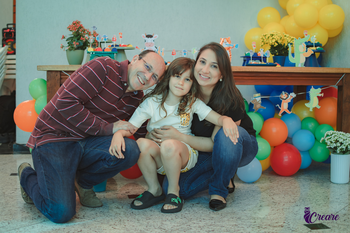familia reunida em frente uma mesa decorada com balões e o tema Banda dos animais, para aniversário infantil.