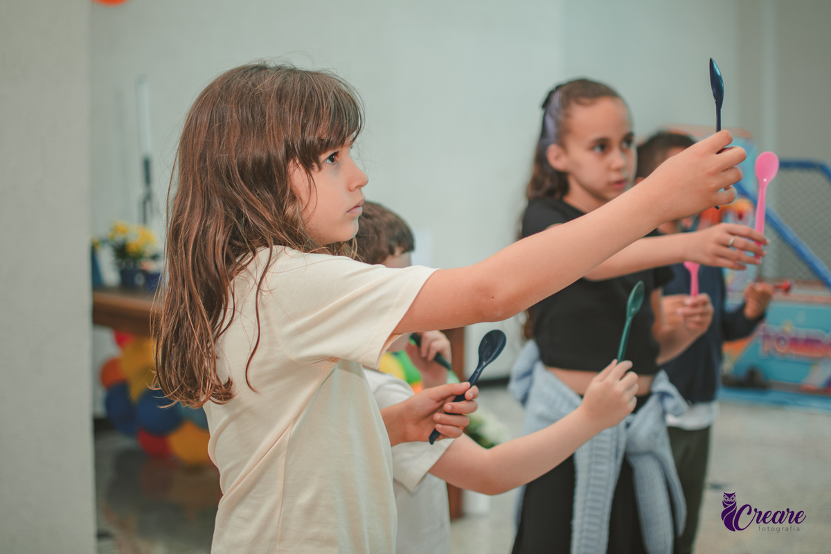 Brincandeiras musicais, feita com colheres, durante festa de aniversário infantil.
