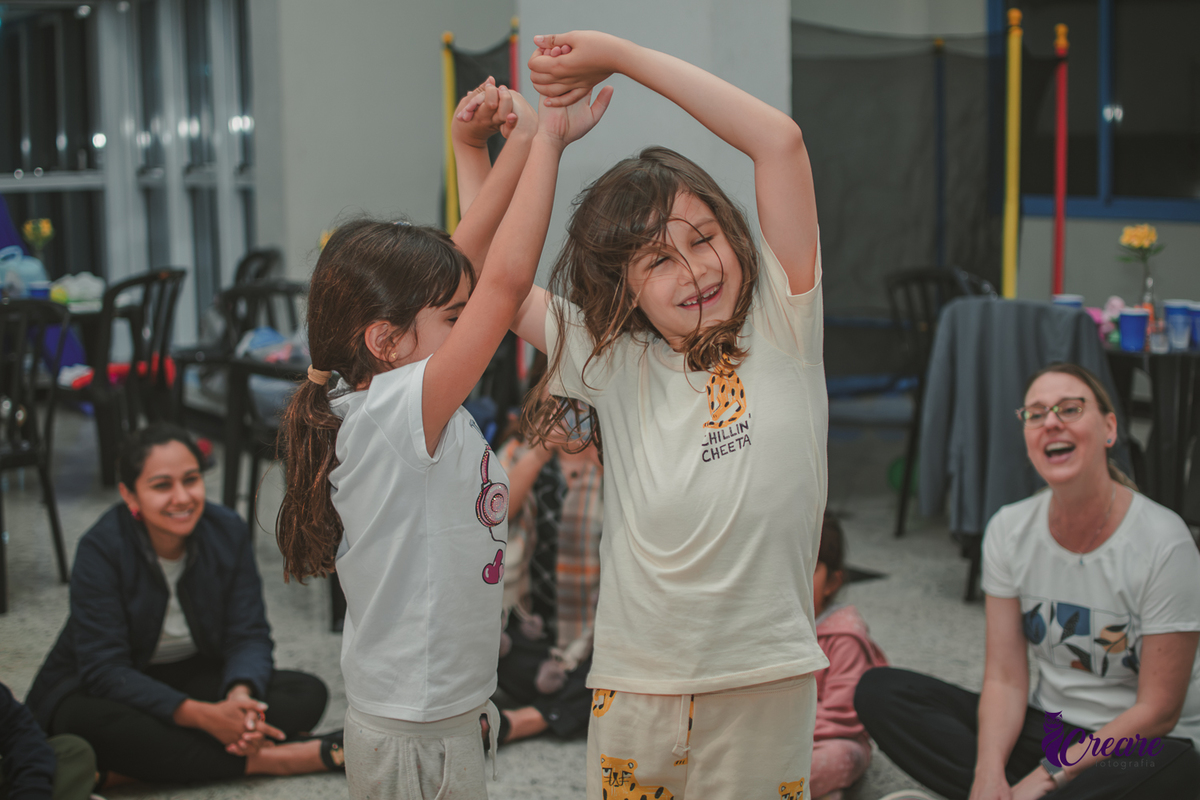 Duas crianças brincando de girar, durante festa de aniversário infantil em casa.
