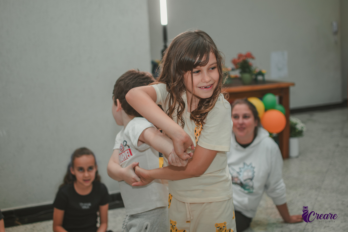 Duas crianças brincando de girar, durante festa de aniversário infantil em casa.