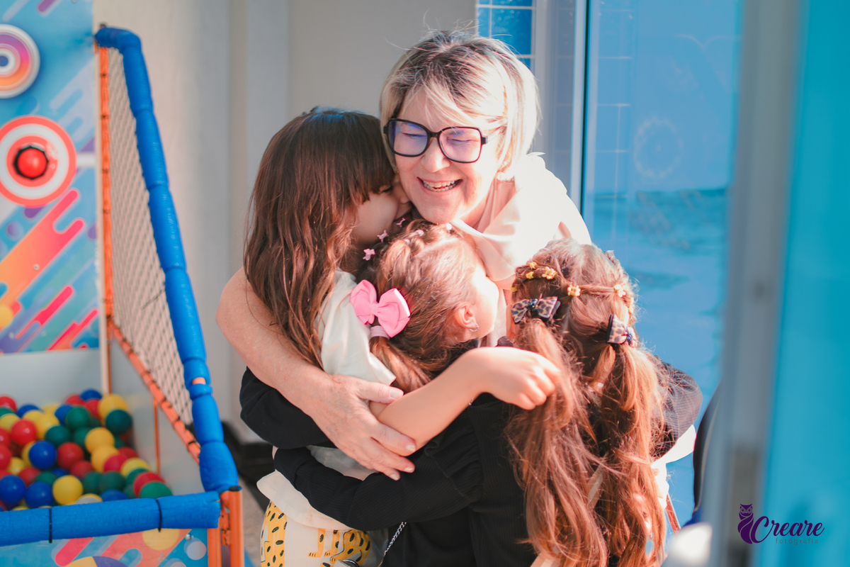 crianças abraçando uma senhara durante aniversário infantil.