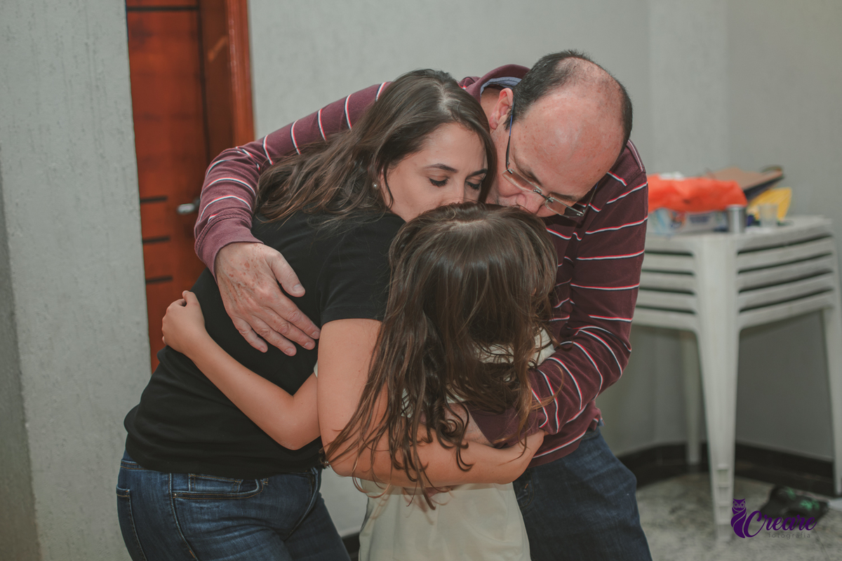 Uma familia se abraçando durante brincadeira de festa de aniversário de 7 anos do filho.
