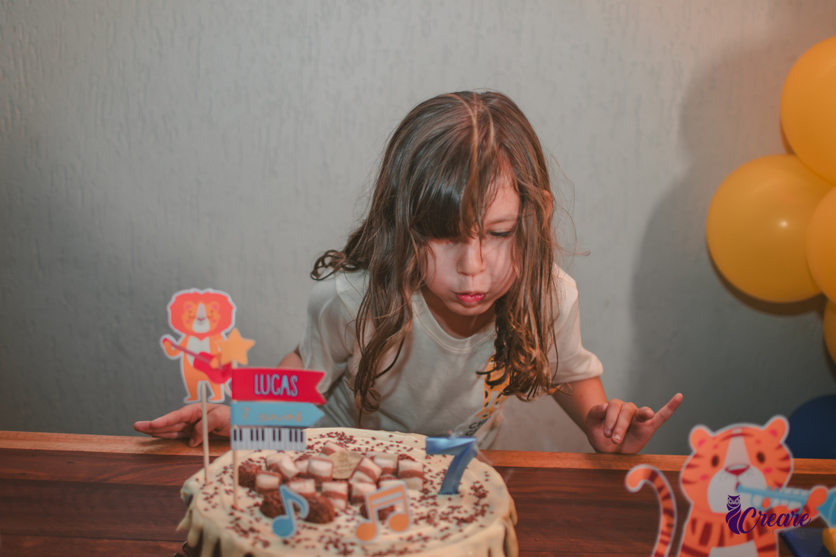 Uma crianlas soprando as velinhas do seu bolo de aniversário.