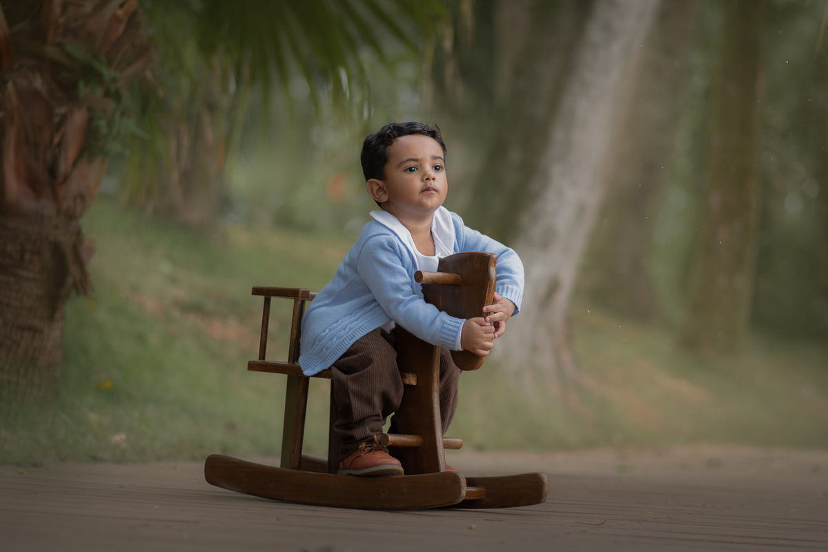 Um menino brincando de balançar em um cavalinho de madeira, durante seu ensaio fotográfico de 2 anos em Ribeirão Pires.
