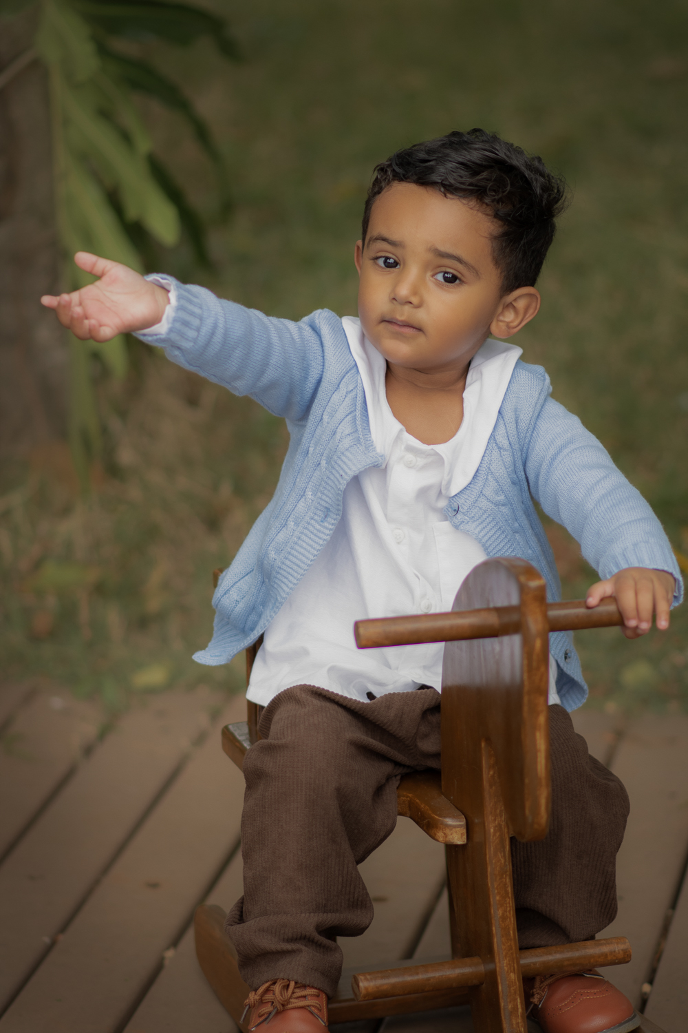 Um menino brincando de balançar em um cavalinho de madeira, durante seu ensaio fotográfico de 2 anos em Ribeirão Pires.