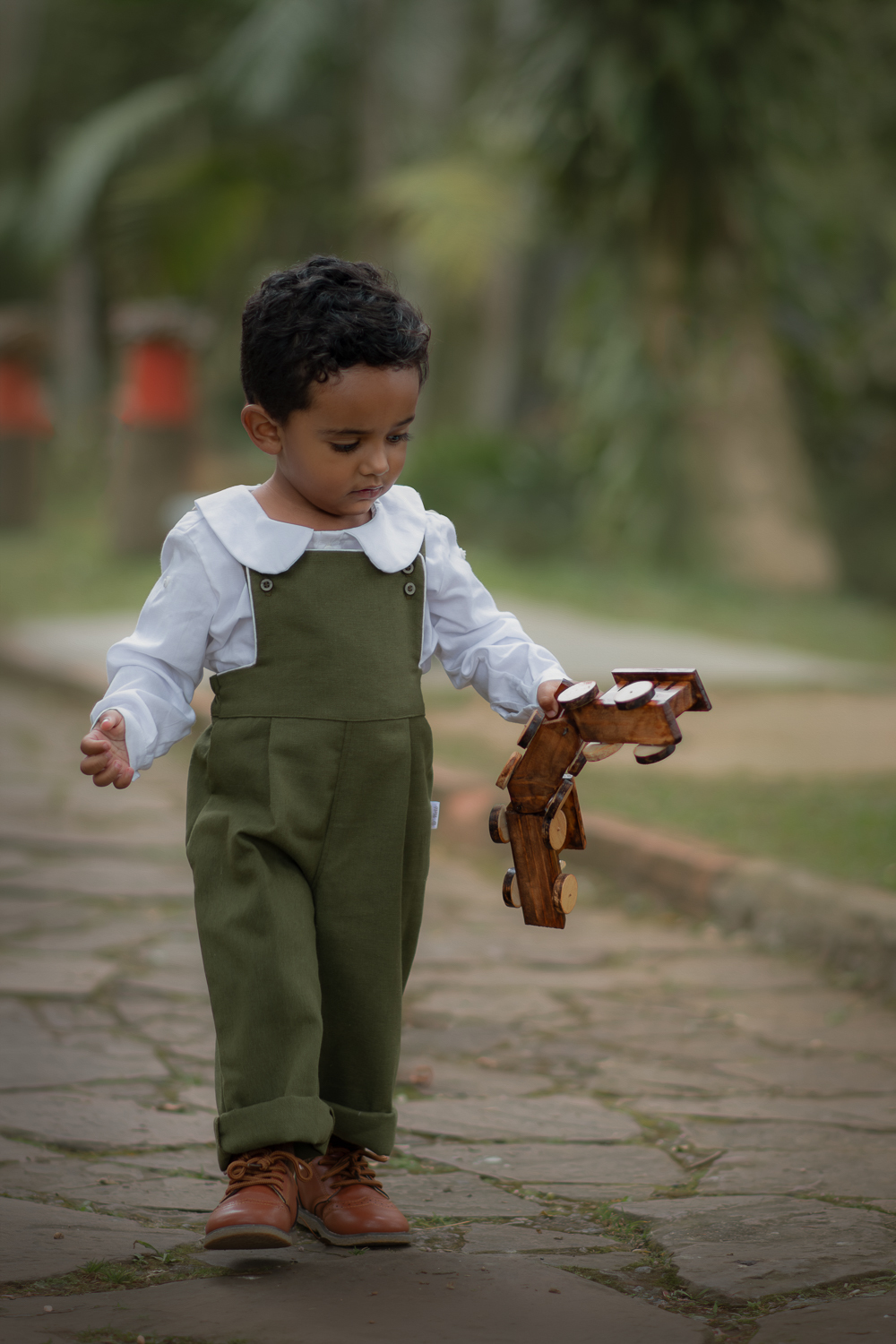 Um menino de 2 anos, segurando um trem de meadeira, durante seu ensaio fotográfico em Ribeirão Pires.