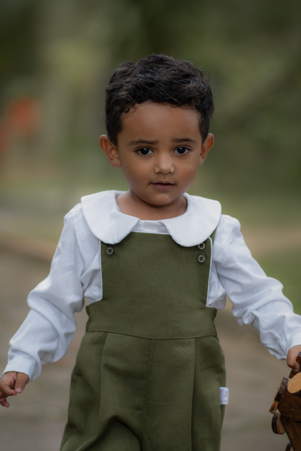 Um menino de 2 anos, segurando um trem de meadeira, durante seu ensaio fotográfico em Ribeirão Pires.