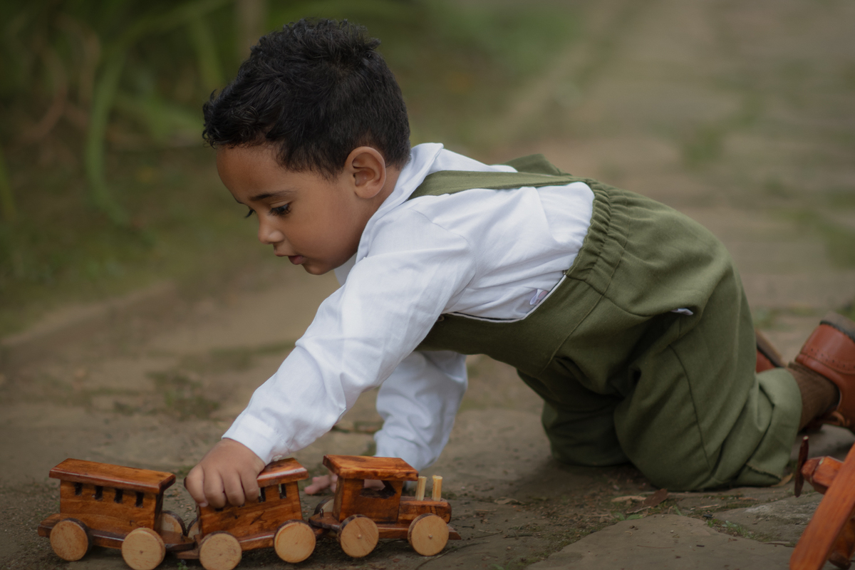 Um menino de 2 anos, empurrando um trem de meadeira, durante seu ensaio fotográfico em Ribeirão Pires.