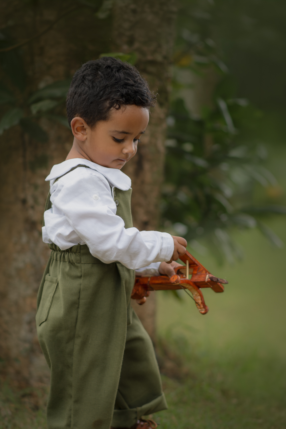 Um menino de 2 anos, segurando um avião de meadeira, durante seu ensaio fotográfico em Ribeirão Pires.