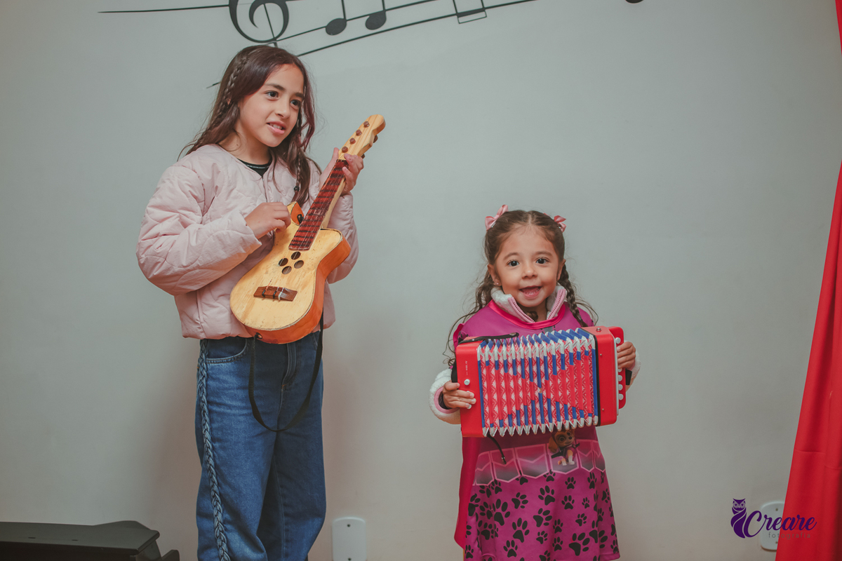 Duas crianças brincando de bandinha com instrumentos, durante festa de aniversário infantil.