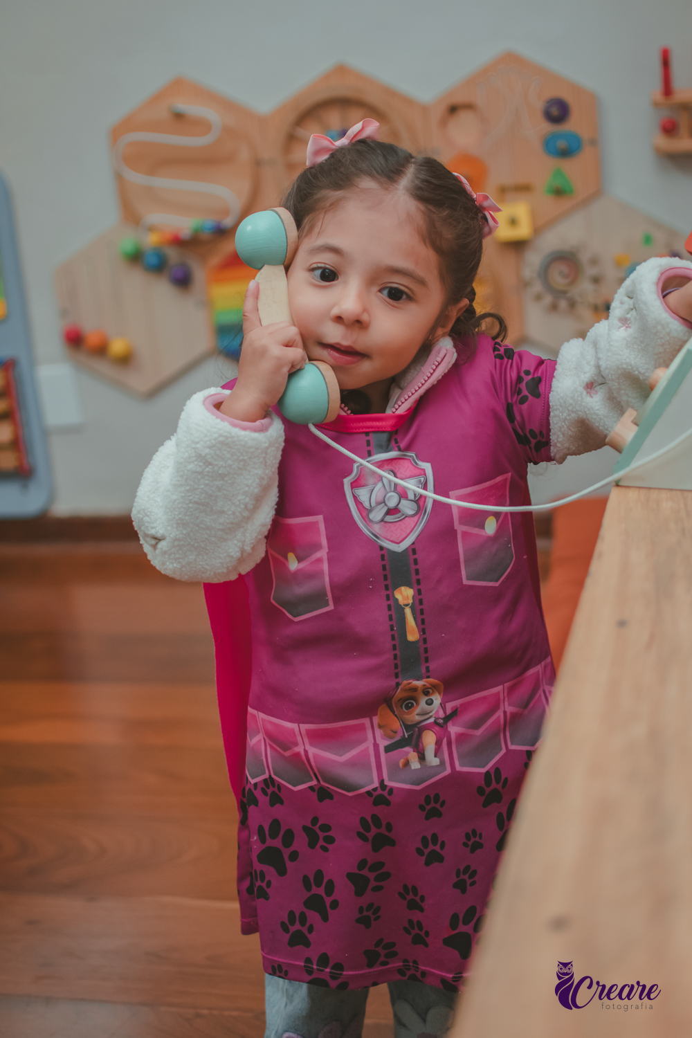 Uma criança, brincando com um telefone de madeira, durante sua festa de aniversário.