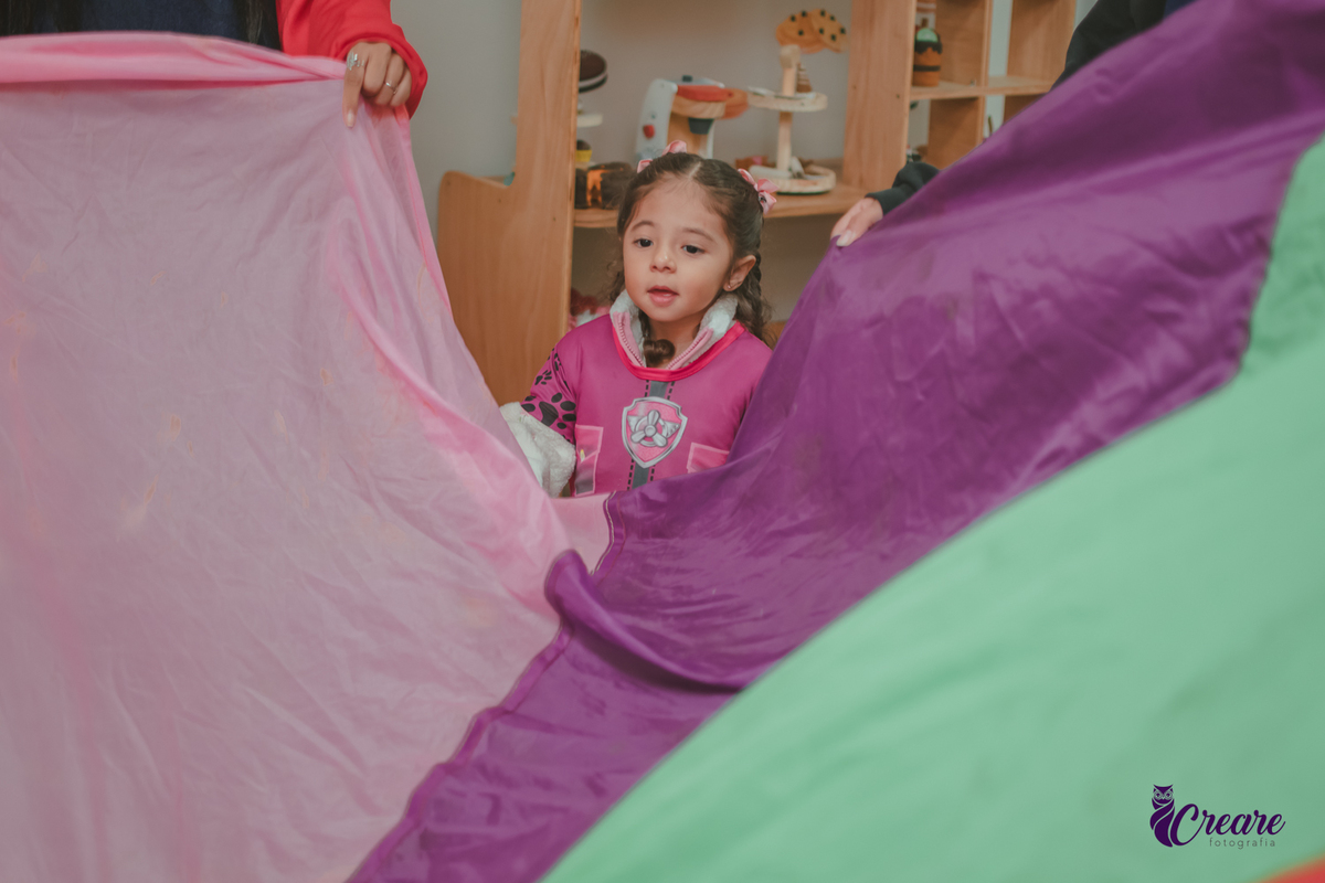 Uma crianças brincando com um tecido colorido, durante sua festa de aniversário.