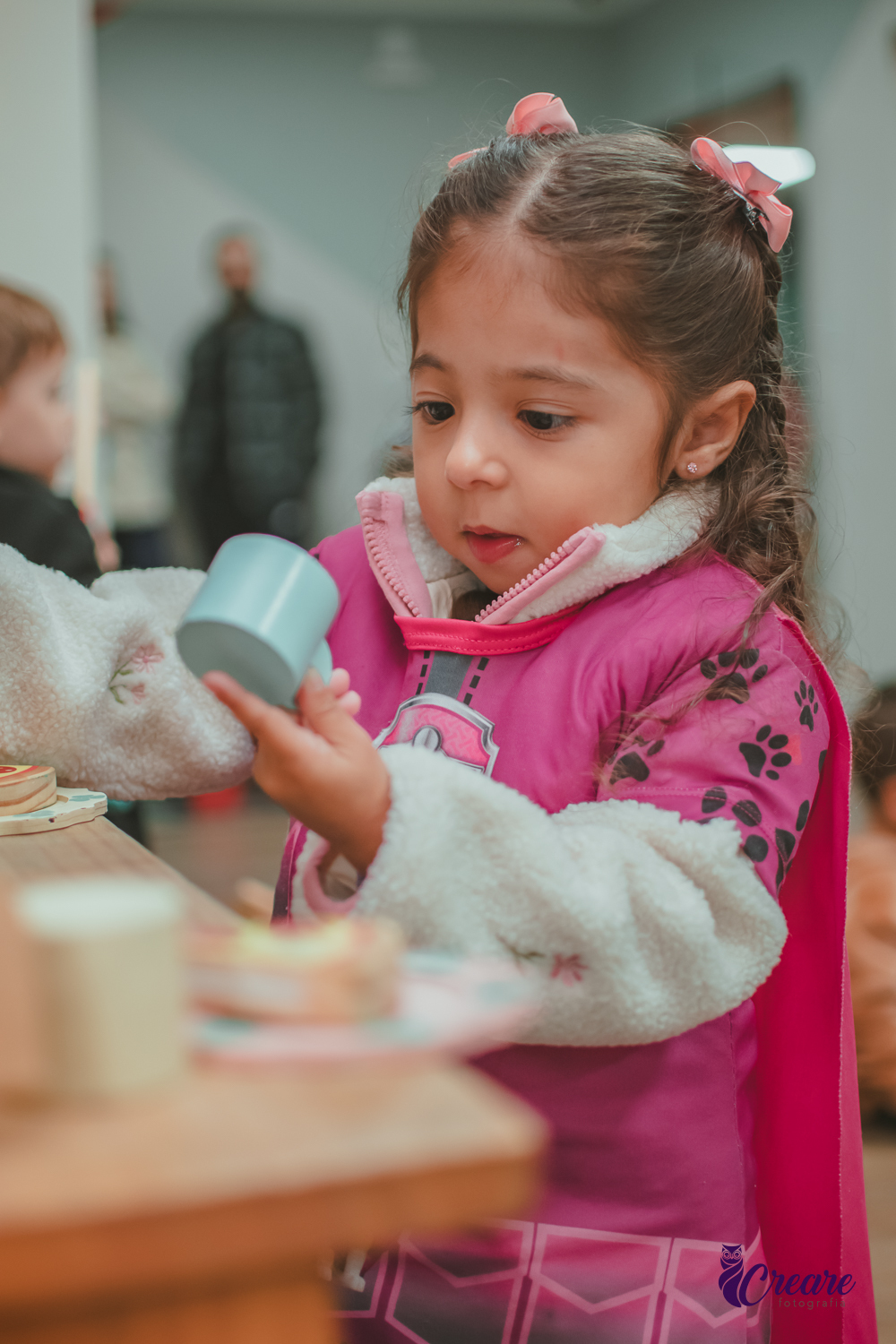Uma criança, brincando com uma xícara de brinquedo, durante sua festa de aniversário.