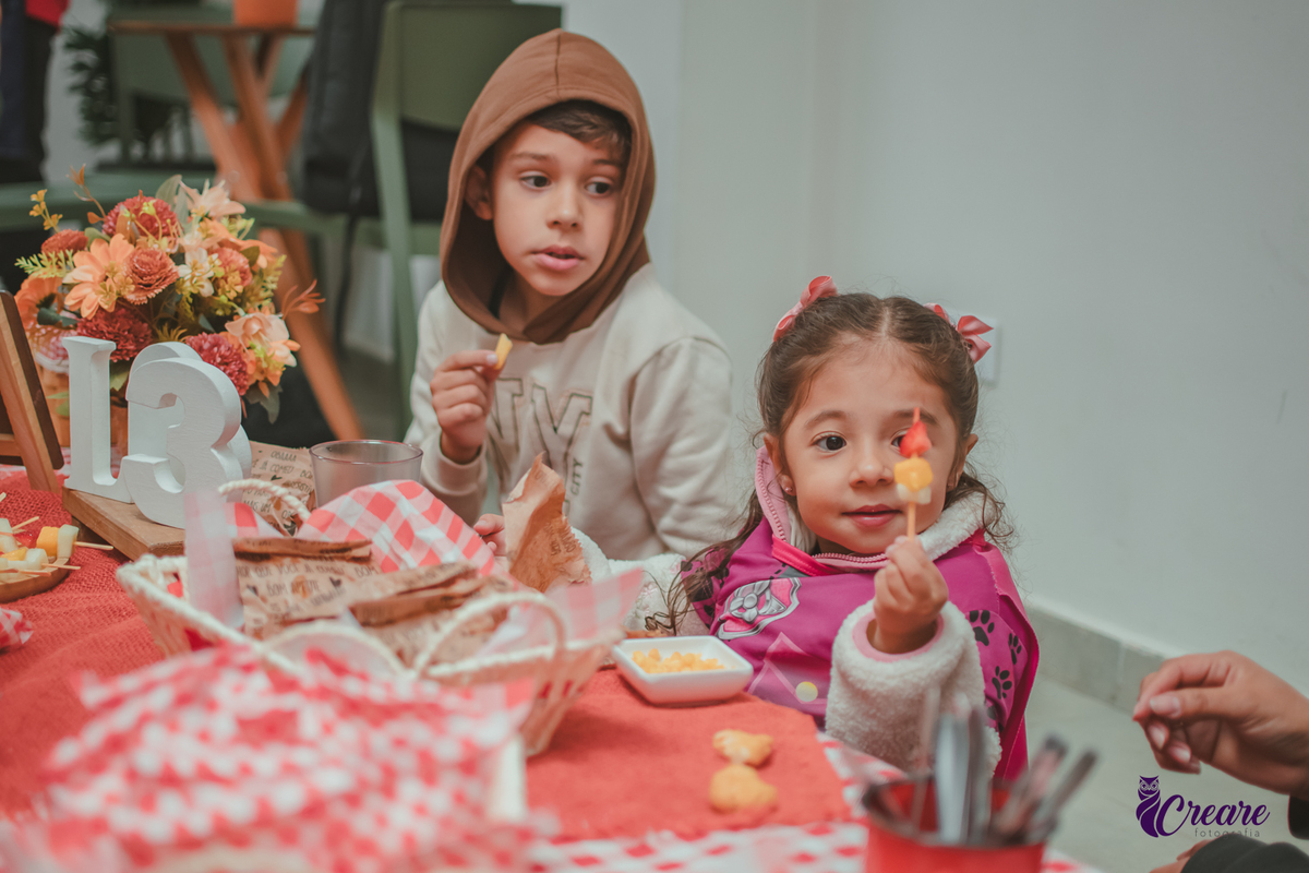Uma crianças, na hora do lanchinho durante sua festa de aniversário de 3 anos.