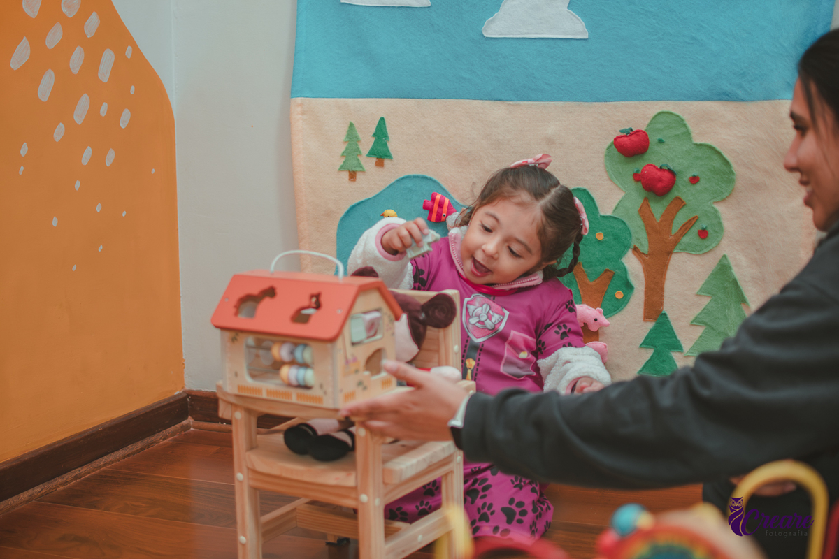 Uma criança brincando com uma casinha de madeira, durante sua festa de aniversário.
