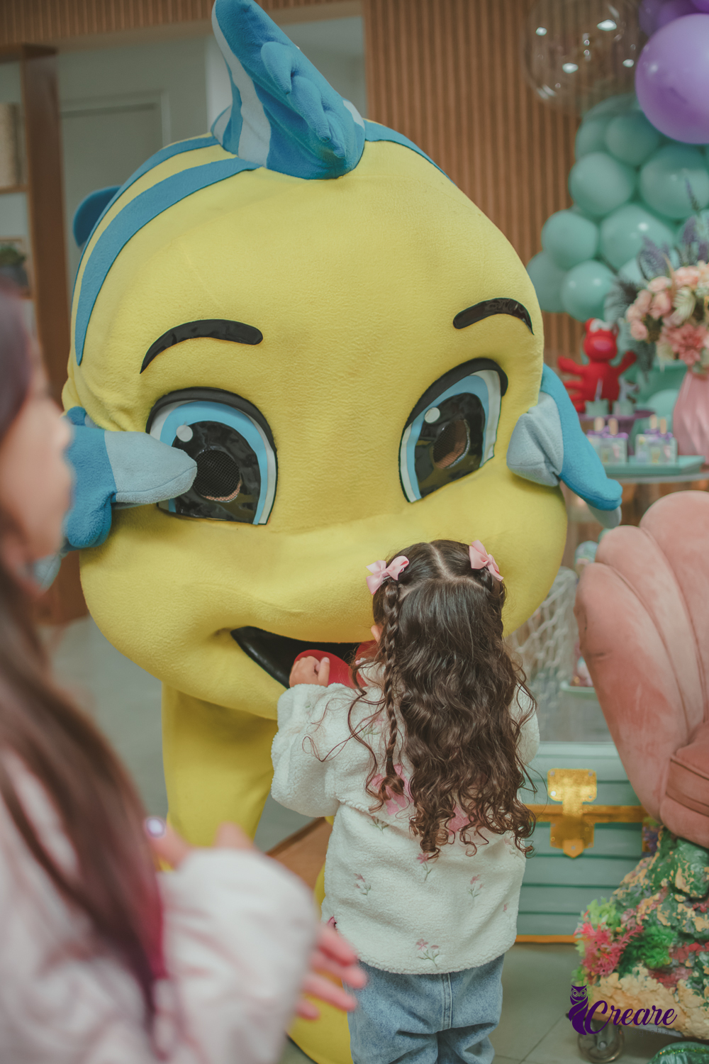 Uma criança abraçando o personagem Linguado, do filme a pequena Sereia, durante a sua festa de aniversário.