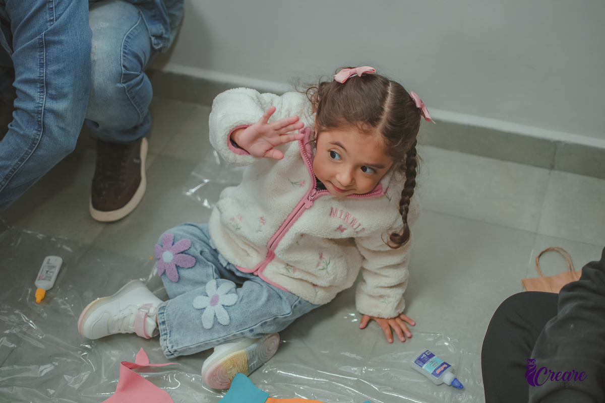 Uma criança acenando para outra pessoa, durante sua festa de aniversário de 3 anos.