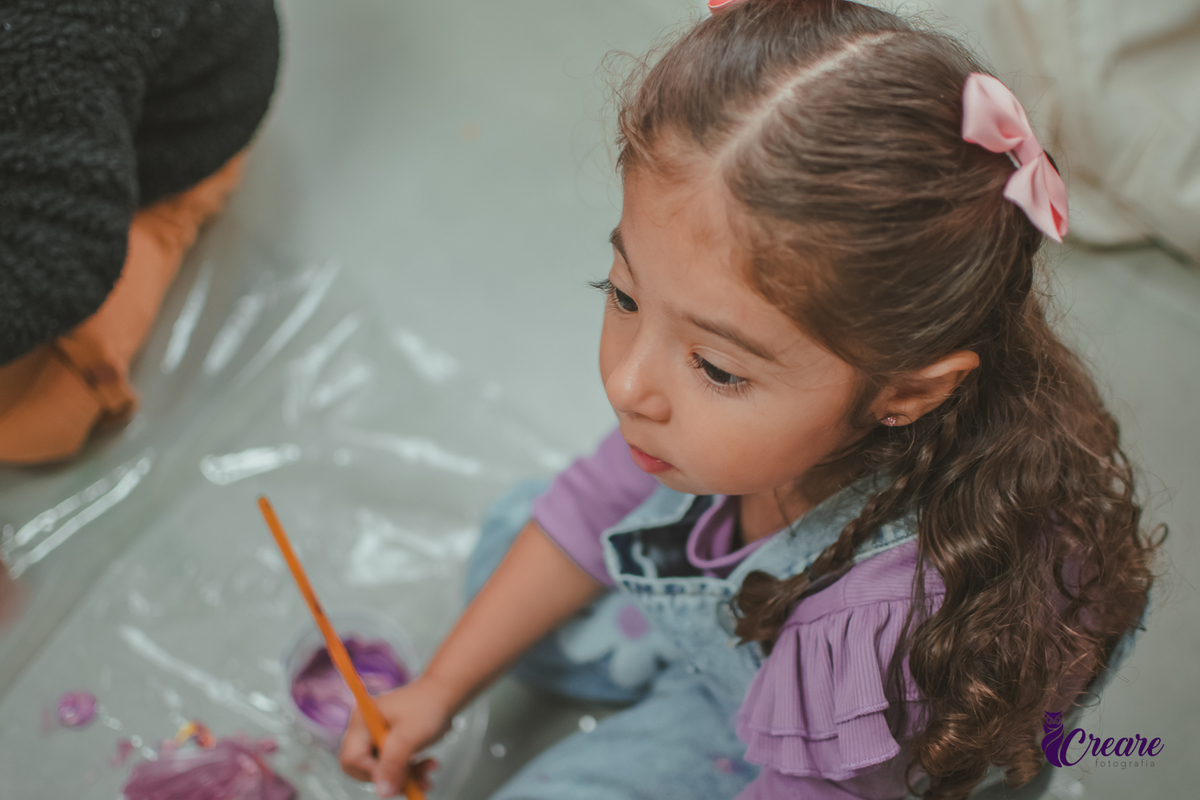 Uma Criança fazendo atividade de pintar gesso, durante festa de aniversário infantil.