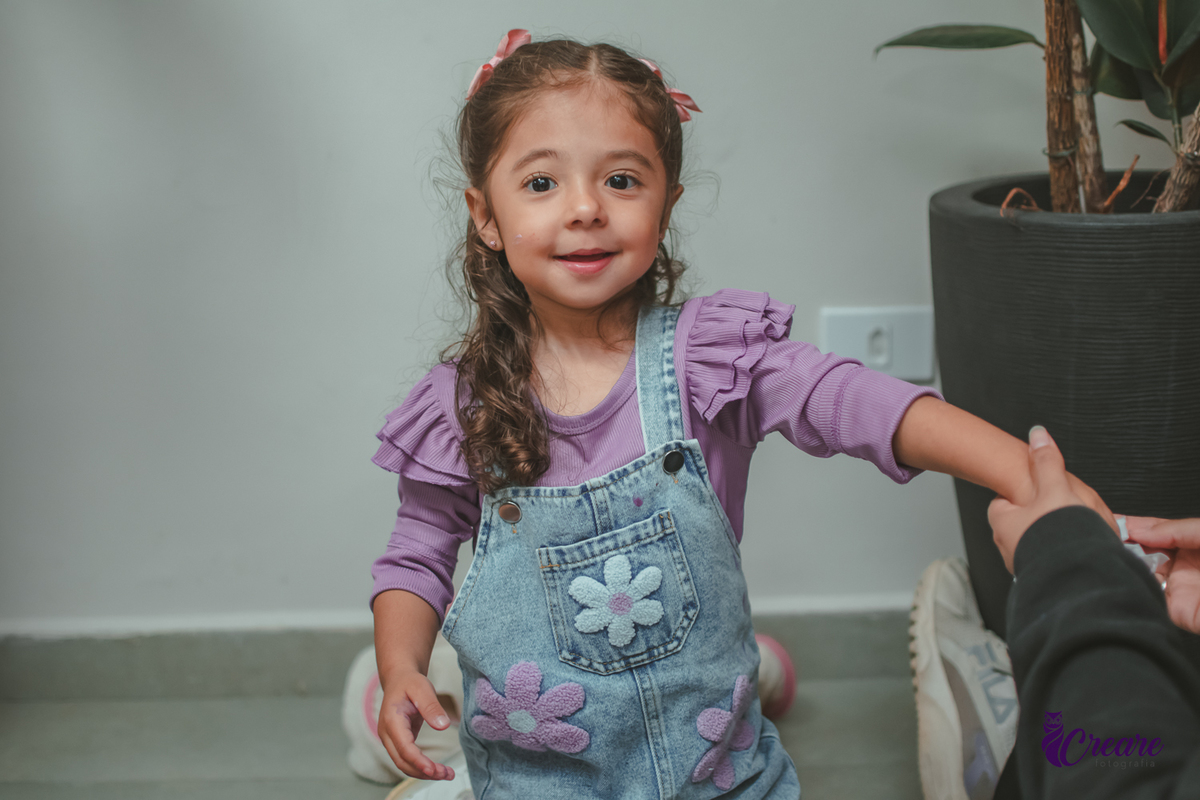 Uma criança sorrindo, durante sua festa de aniversário de 3 anos.