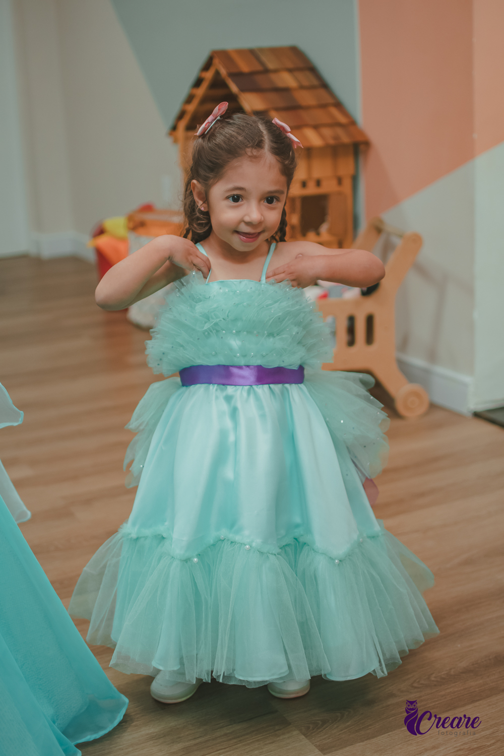 Uma criança feliz, usando seu vestido verde água, durante sua festa de aniversário.