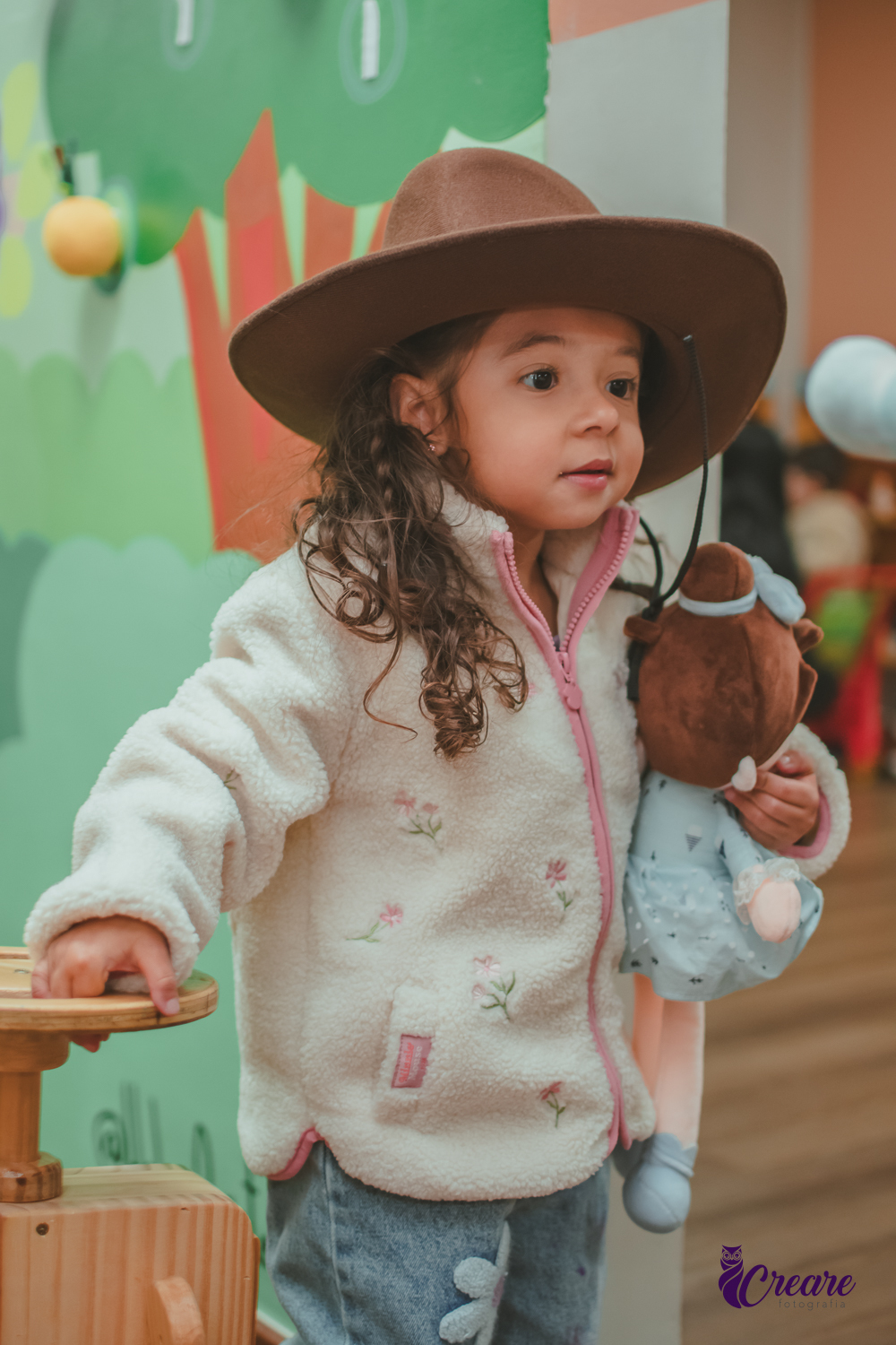 Uma criança usando chapéu de cowboy,durante sua festa de aniversário de 3 anos.