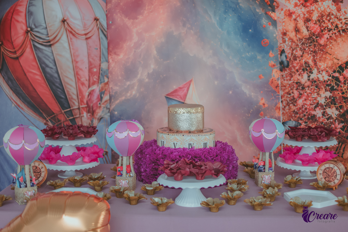 mesa decorada com um bolo roxo, balões e docinhos para festa de aniversário de 1 ano.