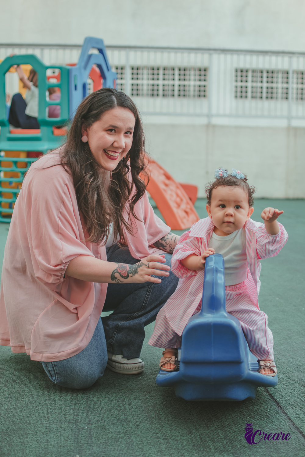 Uma bebê brincando com sua mãe em um parquinho de condomínio, durante festa de aniversário de 1 ano.