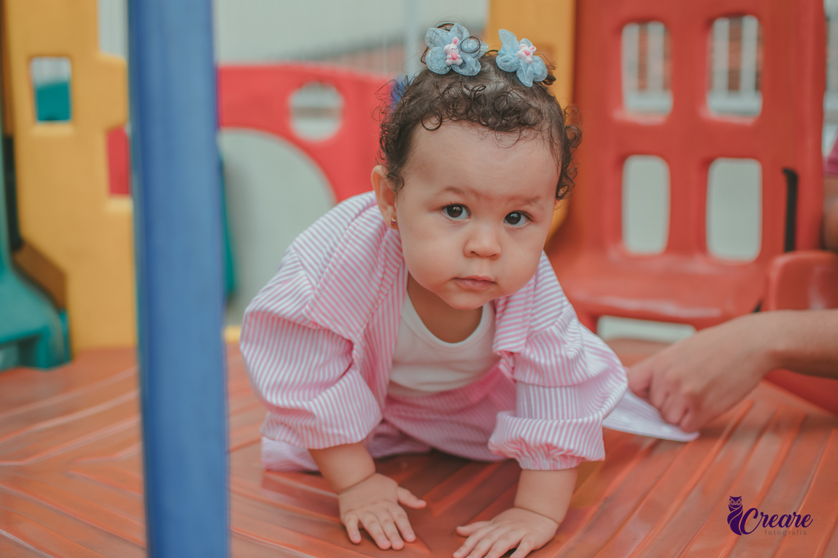 Uma bebê de 1 ano, brincando no parquinho do condomínio, durante sua festa de aniversário em casa.