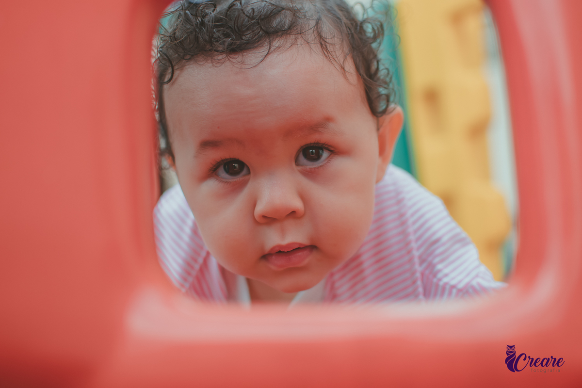 Uma bebê de 1 ano, brincando no parquinho do condomínio, durante sua festa de aniversário em casa.